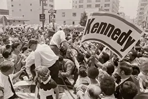 Robert F. Kennedy Shaking Hands Near Large Campaign Signs