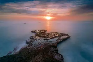Arniston Prints: A rocky outcrop reaching out to the sun peeping through the clouds at Arniston with a long exposure smoothing out