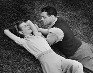 Romantic couple lying on grass, (B&W), elevated view