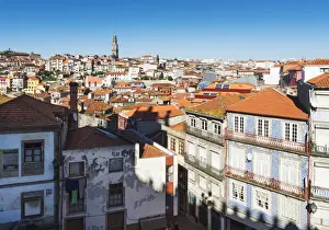 Rooftops of houses and a tower in the distance against a blue sky