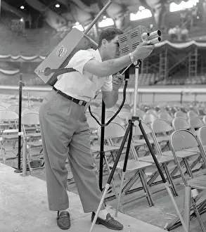 Prints of (Original Caption). NBC Field Engineer Sal Benza tries out a walkie-lookie, or portable TV camera for the first time on the Convention Hall floor Vintage Car Collection Prints: Sal Benza Looking Through Camera