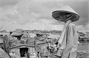 Prints of A Vietnamese woman, wearing a traditional non la hat, standing before an array of sampans moored on an embankment of the Saigon River as it flows through Saigon, Vietnam, 30th August 1965 Vietnam Prints: Sampans On The Saigon River