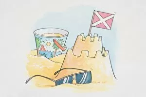 Sand castle with flag, bucket and pair of sunglasses