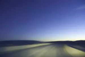 Sand road through dunes, lit by headlights, night (blurred motion)