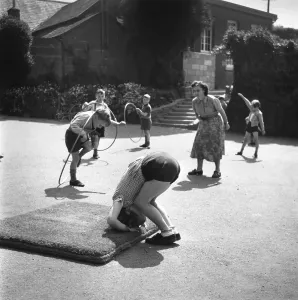 Prints of 3rd July 1945: Children exercising with hoops and a gym mat in a yard outside a village school in Parracombe, Devon. A teacher supervises them on this summer day A Photographic Legacy: School Exercises