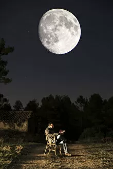 Images Dated 25th September 2015: Seated man reading a book in the moonlight