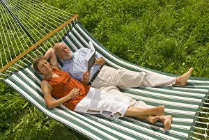 Read Prints: Senior citizen couple lying in a hammock, woman listening to music, man reading a book