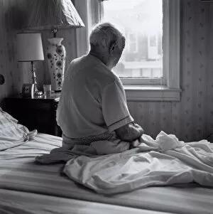 Images Dated 9th June 2004: Senior man sitting on bed facing window