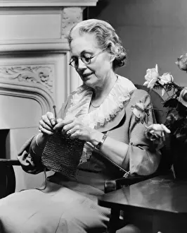 Pince Nez Prints: Senior woman knitting in living room, (B&W)