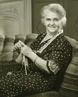 One Senior Woman Only Prints: Senior woman knitting in living room, (B&W), portrait