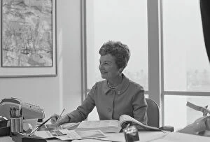 Book Collection: Senior woman sitting at desk writing on notepad, smiling