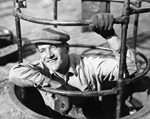 Sewer worker descending below street, (B&W), close-up