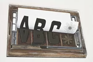 Sheet of paper peeling away from a printing forme imprinted with the letters ABC and image of a flower