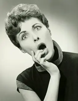 One Mid Adult Woman Only Prints: Shocked woman with fingers on lips in studio, (B&W), portrait