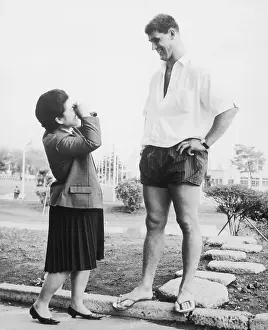Opposites Prints: Small Girl Photographing Tall Man