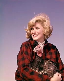 Smiling blonde woman holding thanksgiving turkey