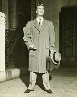Smiling man in top coat standing outdoors, (B&W)