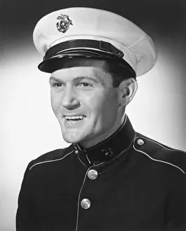 Smiling man in military uniform posing in studio, (B&W), portrait