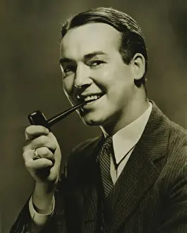 30 35 Years Prints: Smiling man with pipe in mouth posing in studio, (B&W), close-up, portrait
