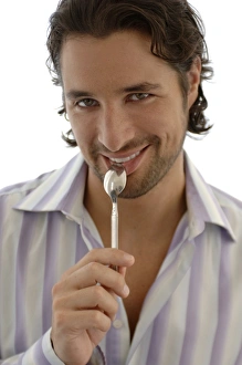 Desire Gallery: Smiling man with a spoon in the mouth, snacking