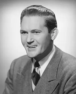 Smiling man in studio, (B&W), portrait