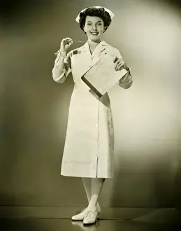 Smiling nurse holding thermometer and files in studio, (B&W), portrait