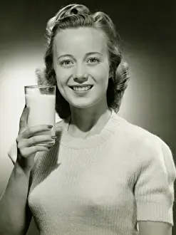 Hair Style Prints: Smiling woman holding glass of milk in studio, (B&W), portrait