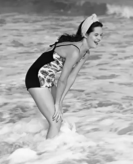 Bending Down Prints: Smiling woman standing in sea, (B&W)