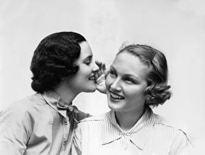 Two Smiling Women The 1 Wearing The Blouse With A Bowtie Is Wispering A Secret In The Ear