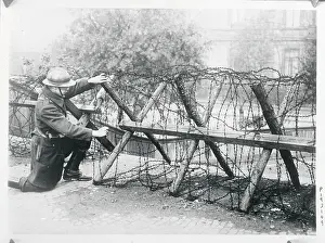 Soldier Stooping to Work on Fence