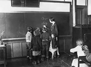 Prints of A teacher writes animal names on the blackboard to teach her young pupils how to spell, 1930. (Photo by FPG/Hulton Archive/Getty Images) Black and White Images Capturing the Essence of Mid-20th Century: Spelling Lesson