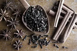 Spices, cloves, star anise and cinnamon sticks with wooden spoon on rustic wood