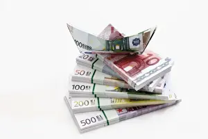 Banknote Prints: Stacked euro notes in bundles with boat made from notes