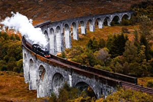 Viaduct Views Gallery: Steam train crossing the Glenfinnan bridge with autumn colors in Scotland