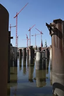 Steel pillars in the water in front of construction cranes in the new development area of HafenCity, Hamburg, Germany