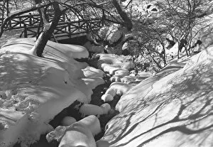Stream and wooden bridge covered with snow