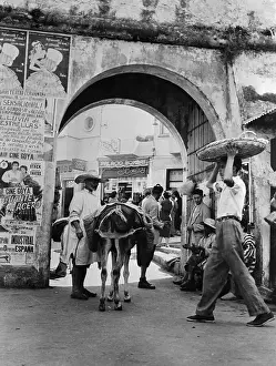 Street Merchants Standing Under Arch with Spanish Posters