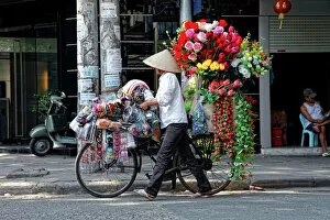 Walking Gallery: A street vendor with a bicycle selling her flowers in Hanoi, Vietnam, Asia