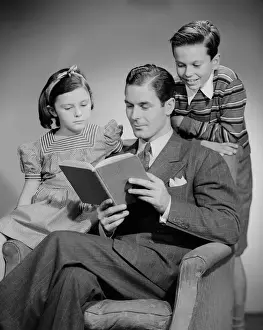10 11 Years Prints: Studio shot of father with two children (10-11) reading book