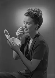Beauty Concept Prints: Studio shot of young woman applying make-up