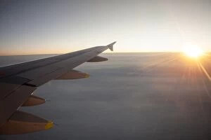 Morning Sky Gallery: Sunrise from an airplane above the clouds with wing unit, above Norway