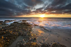 Images Dated 11th December 2014: Sunrise landscape of ocean with waves clouds and rocks on beach