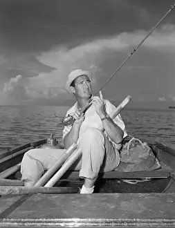 Ted Williams Sitting in Boat with Extended Fishing Rod