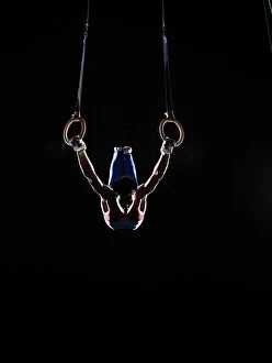 Recreational Pursuit Collection: Teenage (16-17) male gymnast practicing on rings against black background