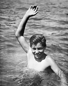 Only Teenage Boys Prints: Teenage boy (16-17) standing deep in water, waving, (B&W), portrait