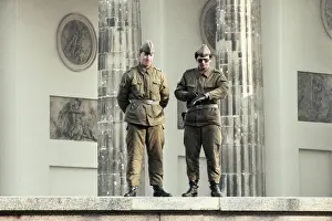 Prints of East German border guards stand on top of the Berlin Wall with the 18th-century neoclassical Brandenburg Gate behind them on November 12, 1989 in Berlin, Germany Timeless Moments: A Visual Journey Through History’s Defining Images: Television Commercial