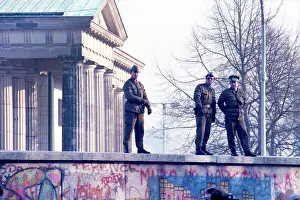 Prints of East German border guards stand on top of the graffiti-covered Berlin Wall with the 18th-century neoclassical Brandenburg Gate behind them on November 12, 1989 in Berlin, Germany Timeless Moments: A Visual Journey Through History’s Defining Images: Television Commercial