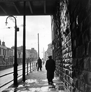 Images Dated 11th March 2016: Tiger Bay; A man walking under a railway bridge in the dockland area of Cardiff