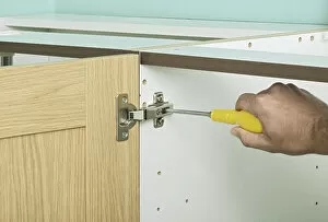 Tightening central screw in a hinge with a screw driver, close up