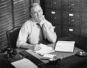 Desk Prints: Tired man working at desk (B&W), portrait